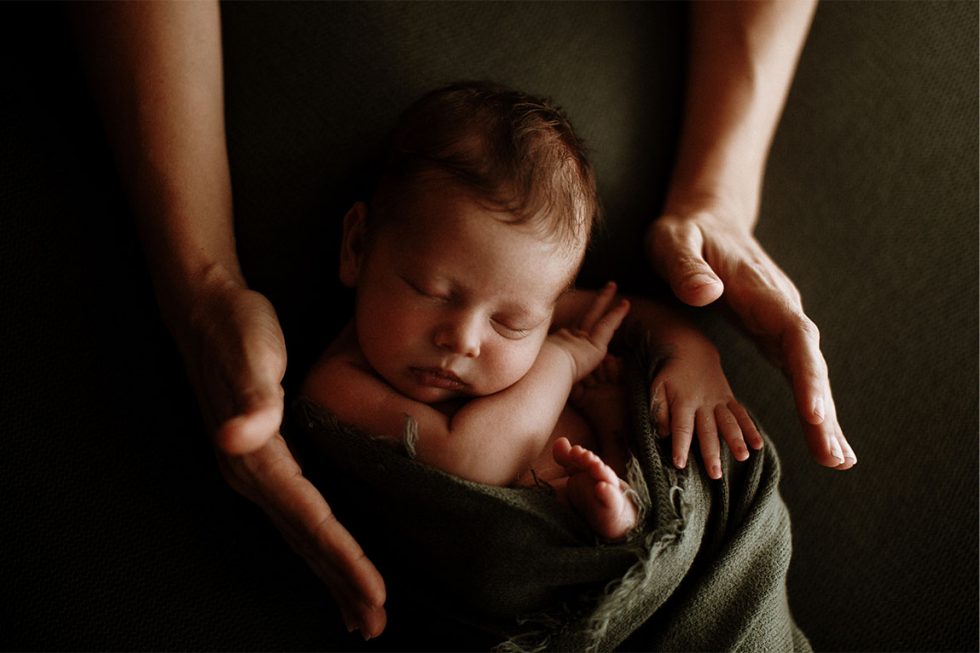 fotografia de un bebe newborn y las manos de su madre