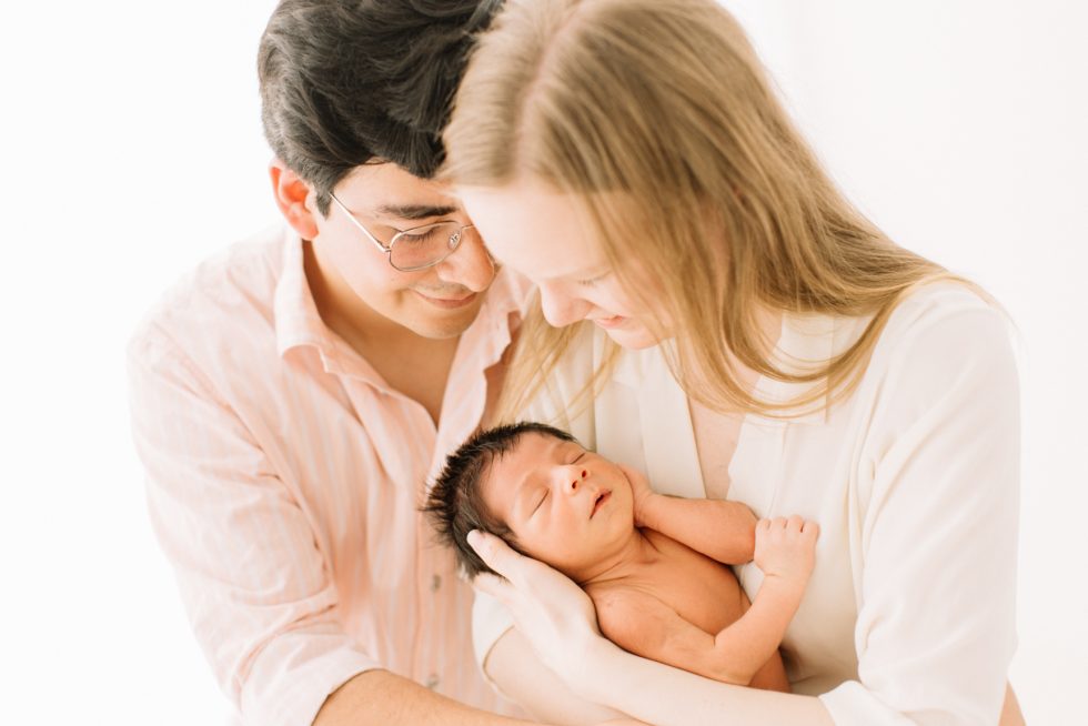 fotografia de unos padres mirando a su hijo recien nacido